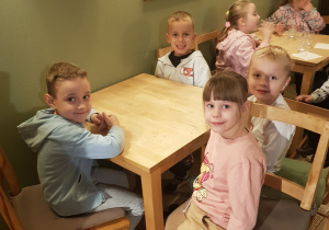 Przedszkolaki siedzące przy stoliczku w oczekiwaniu na przedstawienie