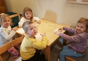 Dzieci siedzące przy stoliczku czekające na przedstawienie