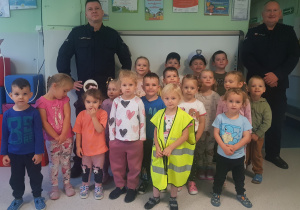 GRUPA NIEBIESKA- dzieci siedzą i stoją, pozując do wspólnego zdjęcia z policjantami
