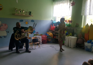 Prezenterka zapowiada utwór muzyczny grany przez muzyka.
